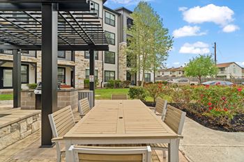 A wooden bench is situated under a black pergola.